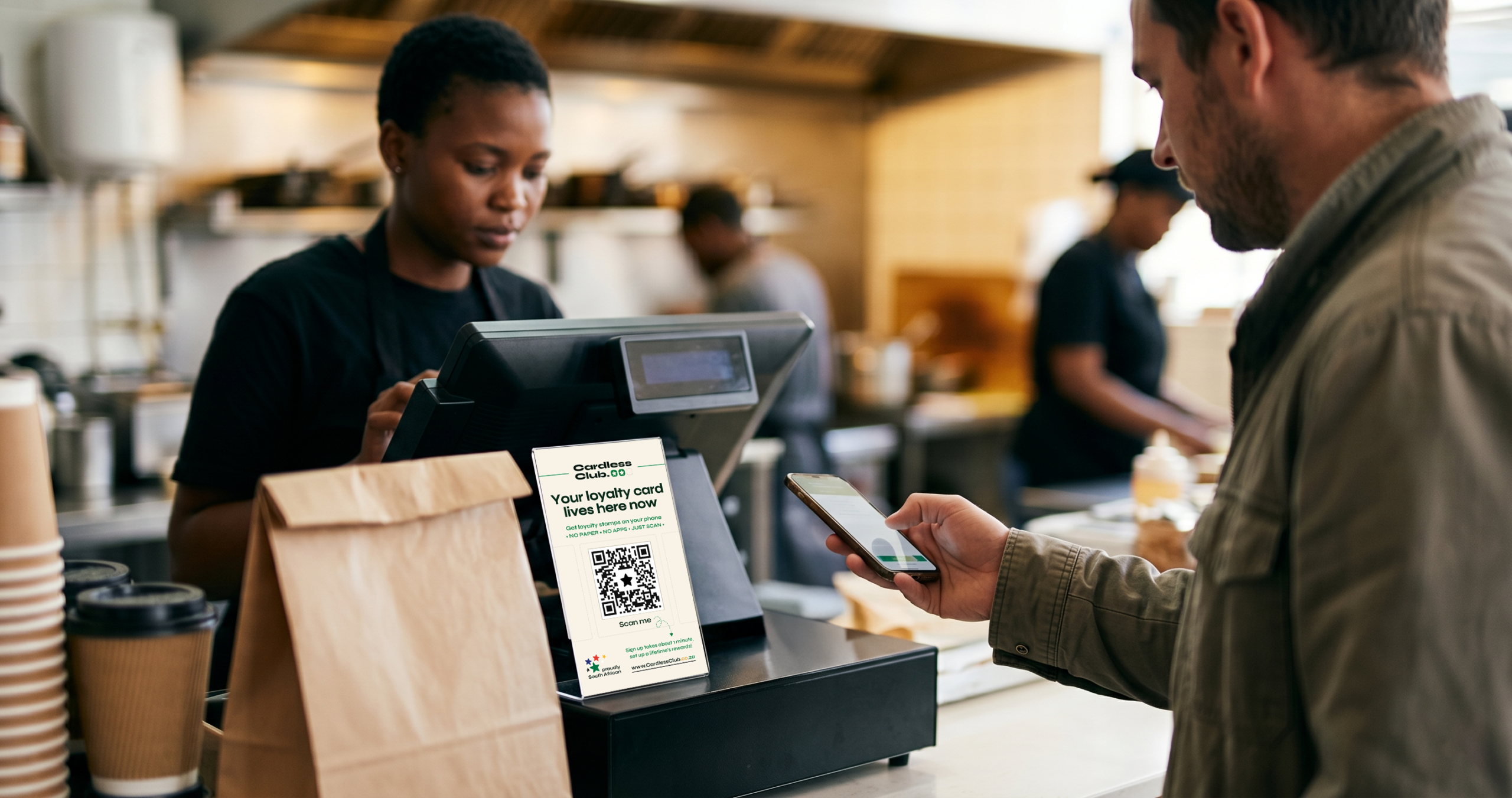 A barista showing a customer where to scan at a coffee shop counter
