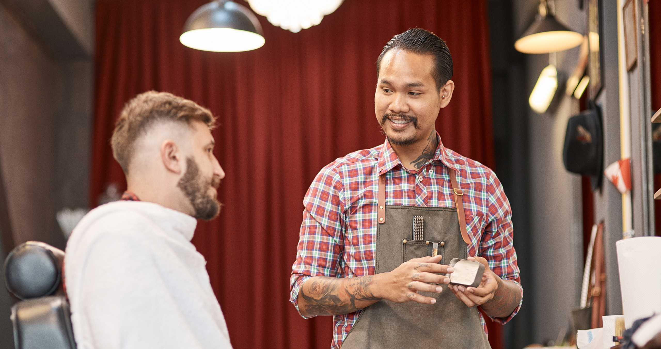A barber scanning a client's phone at the styling chair